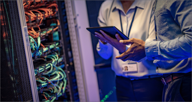 man in server room looking at a tablet