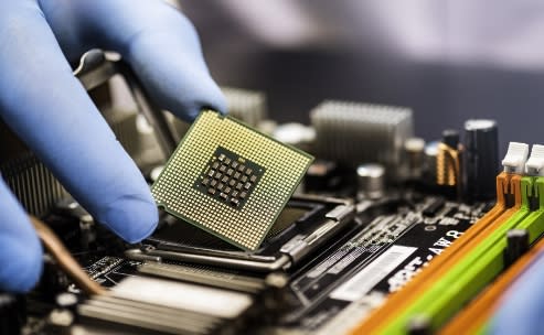 a hand lifting an intel chip with thumb and index finger