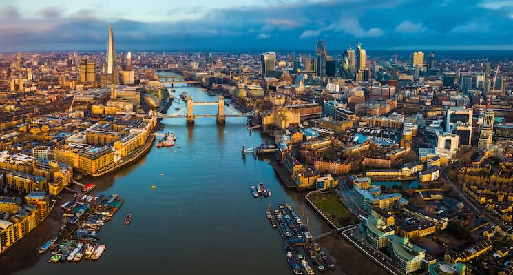 London, England – Panoramic aerial skyline view of London including Tower Bridge with red double-decker bus, Tower of London, skyscrapers of Bank District