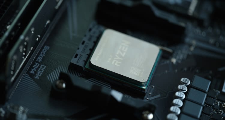 Close-up of an AMD Ryzen processor installed in a motherboard socket, surrounded by various electronic components. The image highlights the CPU's positioning and integration within a high-performance PC build.