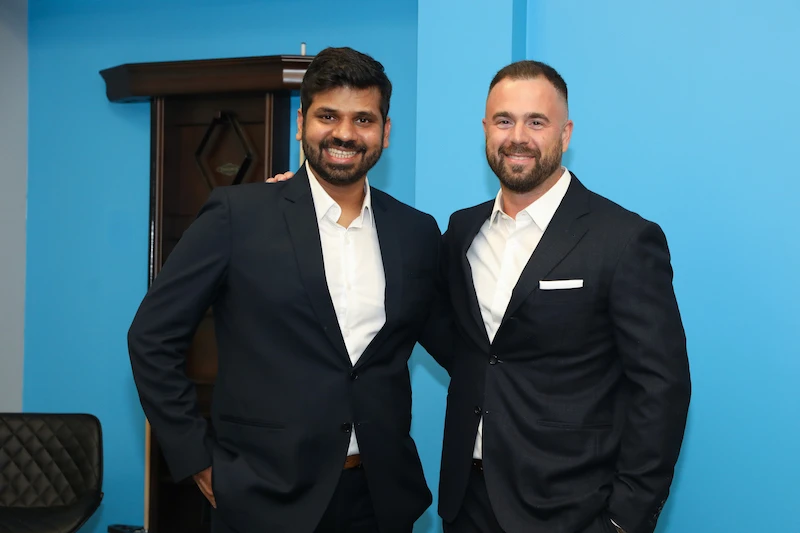 Two employees against a bright blue wall