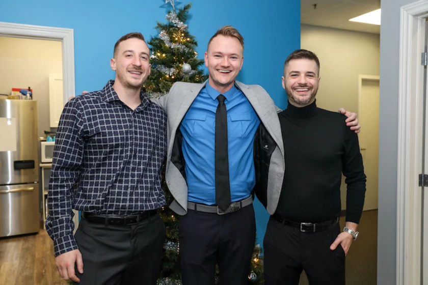 Employees in front of Christmas Tree against a blue wall